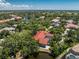 Expansive aerial view of a red-roofed home surrounded by lush landscaping and a tranquil lake in an established community at 26 Saint Croix Way, Englewood, FL 34223
