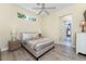 Bedroom with light wood floors, an adjacent bathroom, large windows and a ceiling fan at 26 Saint Croix Way, Englewood, FL 34223
