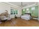 Stylish bedroom featuring wood floors, a green accent wall, and a large arched window at 26 Saint Croix Way, Englewood, FL 34223