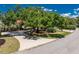 Street view showcasing the home's landscaping and curb appeal with mature trees and a circular driveway at 26 Saint Croix Way, Englewood, FL 34223