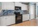 Kitchen with white cabinetry and black appliances, including oven, microwave and custom backsplash at 270 E Wentworth St, Englewood, FL 34223
