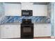 Updated kitchen with sleek black appliances, white cabinets, and custom backsplash at 270 E Wentworth St, Englewood, FL 34223