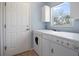Functional laundry room equipped with washer, dryer, overhead cabinets, and natural light from the window at 270 E Wentworth St, Englewood, FL 34223
