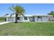 Inviting home exterior featuring a mature palm tree, metal roof, and a well-kept lawn under a clear blue sky at 3246 Yukon Dr, Port Charlotte, FL 33948