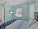 Bedroom with light blue walls, TV on the wall, light carpet and a bed with a light blue patterned comforter at 39 Fairway Rd, Rotonda West, FL 33947
