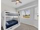 Bright bedroom featuring bunk beds with blue bedding, a ceiling fan, and a sunlit window offering scenic views at 39 Fairway Rd, Rotonda West, FL 33947