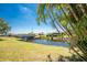Scenic backyard view showcasing a lush green lawn, mature palm trees, and a tranquil canal with a bridge, ideal for relaxation at 4 Pine Valley Ln, Rotonda West, FL 33947