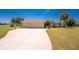 Inviting single-story home features a three-car garage, long driveway, lush lawn, and mature tropical landscaping at 4 Pine Valley Ln, Rotonda West, FL 33947