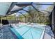 A screened-in pool area featuring a pool, lounge chairs, spa, and lush landscaping at 4065 N Beach Rd # A, Englewood, FL 34223