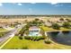 Aerial view of community pool, clubhouse, and surrounding neighborhood with trees, lake and grassy areas at 4207 Fairway Pl, North Port, FL 34287