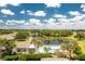 Scenic aerial view of a community pool and clubhouse overlooking a lake, surrounded by trees and landscaping at 4207 Fairway Pl, North Port, FL 34287