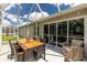 Inviting screened-in porch with a dining set and cozy wicker seating, offering a perfect spot for outdoor entertainment and relaxation at 4207 Fairway Pl, North Port, FL 34287