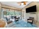 Cozy screened porch with comfortable seating, a ceiling fan, TV and an outdoor view at 4207 Fairway Pl, North Port, FL 34287