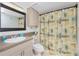 Cozy bathroom featuring neutral colors, granite countertops, and a shower with a patterned curtain at 5030 N Beach Rd # 1, Englewood, FL 34223