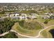Aerial view of a residential neighborhood with multiple homes, golf course, ponds, and green spaces in a community at 56 Long Meadow Ct, Rotonda West, FL 33947