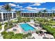 A beautiful community pool surrounded by lush landscaping and palm trees with multiple condos in the background at 5700 Gulf Shores Dr # A312, Boca Grande, FL 33921