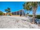 Exterior view showcasing the home with a screened porch, surrounded by palm trees and landscaping at 6029 Manasota Key Rd, Englewood, FL 34223