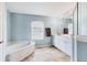 Bathroom featuring a garden tub, double vanity with ample lighting and blue accent wall at 6062 Spinnaker Blvd, Englewood, FL 34224