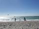 People enjoying a sunny day on the beach, playing in the waves, with clear skies and calm water at 6062 Spinnaker Blvd, Englewood, FL 34224