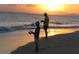 Two figures fishing on the beach at sunset, with calm waters and colorful sky, creating a peaceful scene at 6062 Spinnaker Blvd, Englewood, FL 34224