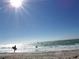 Scenic beach view of surfer and swimmer enjoying the waves on a bright sunny day at 6062 Spinnaker Blvd, Englewood, FL 34224