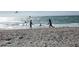 Beach view featuring people playing in the water with the sun shining and blue skies at 6062 Spinnaker Blvd, Englewood, FL 34224