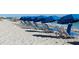 Beach chairs and umbrellas on a sandy shore, with clear blue water and sky for a relaxing experience at 6062 Spinnaker Blvd, Englewood, FL 34224