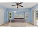 Bright, light blue bedroom features a ceiling fan, white bookcase headboard and tile flooring at 6062 Spinnaker Blvd, Englewood, FL 34224