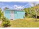 Exterior of a turquoise storage building with a white door near a grassy lawn at 6062 Spinnaker Blvd, Englewood, FL 34224