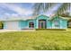 Charming turquoise home featuring a well-manicured lawn and an attached two-car garage at 6062 Spinnaker Blvd, Englewood, FL 34224