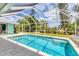 Screened in pool with blue water, concrete deck, and view of backyard at 6062 Spinnaker Blvd, Englewood, FL 34224