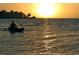 A Personal paddles a kayak on a serene body of water during a beautiful sunset, framed by silhouetted trees at 6062 Spinnaker Blvd, Englewood, FL 34224