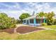 Landscaped backyard with flower beds and stepping stones leading to a turquoise home at 6062 Spinnaker Blvd, Englewood, FL 34224