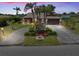 Charming home featuring lush landscaping, mature palm trees, and a spacious driveway leading to a two-car garage at 6305 Shalimar St, Port Charlotte, FL 33981
