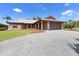 Exterior elevation of a single-story home with a large driveway and well-maintained lawn at 6305 Shalimar St, Port Charlotte, FL 33981