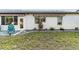 Charming single-story home featuring awnings, a cozy patio chair, and a beautifully landscaped yard with decorative planters at 667 Foxwood Blvd, Englewood, FL 34223
