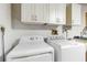 Laundry room with modern white washer and dryer and overhead cabinets for storage at 667 Foxwood Blvd, Englewood, FL 34223