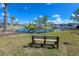 Relaxing pond view with a bench, mature trees, and lush landscaping at 6800 Placida Rd # 262, Englewood, FL 34224