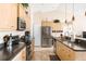 Bright kitchen featuring stainless appliances, light wood cabinetry, black countertops, and tile flooring throughout at 7089 Benson St, Englewood, FL 34224