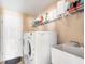 Clean laundry room featuring a washing machine, dryer, utility sink, and storage shelves at 7089 Benson St, Englewood, FL 34224