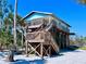 Charming elevated beach home with a wooden staircase and inviting porch at 8472 Grand Ave, Placida, FL 33946