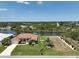 Aerial shot of a waterfront property with a lush lawn, palm trees, and a private boat dock on the canal at 9158 Melody Cir, Port Charlotte, FL 33981