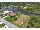 Scenic aerial view of a canal-front home with a spacious lawn, landscaping, and private boat dock access at 9158 Melody Cir, Port Charlotte, FL 33981