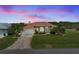 Sunset view of home with manicured lawn, mature palms, and a beautiful driveway at 9158 Melody Cir, Port Charlotte, FL 33981
