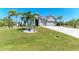 Well-manicured front yard with lush green grass and mature palm trees enhances the home's curb appeal at 9283 Newnan Cir, Port Charlotte, FL 33981