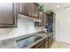 Well-equipped kitchen featuring dark cabinetry, granite countertops, tile backsplash, and stainless steel appliances at 9283 Newnan Cir, Port Charlotte, FL 33981