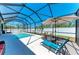 Sunny lanai featuring a screened pool, lounge chairs, umbrella, and well maintained landscaping at 9283 Newnan Cir, Port Charlotte, FL 33981