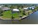 Aerial view showcasing the waterfront property with a pool, dock, and lush landscaping at 9404 Arnaz Cir, Port Charlotte, FL 33981