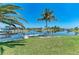 Waterfront backyard featuring a wooden dock and vibrant green lawn with palm trees at 9404 Arnaz Cir, Port Charlotte, FL 33981