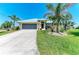 Inviting exterior of home showcasing a manicured lawn, mature palm trees, and an attached two-car garage at 9404 Arnaz Cir, Port Charlotte, FL 33981